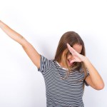 Photo of funky beautiful blonde girl wearing striped t-shirt on white background show disco move dab