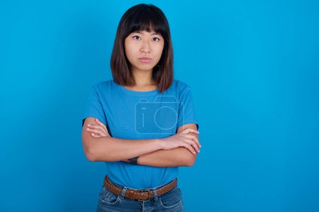 Photo for Picture of angry young asian woman wearing blue t-shirt against blue background looking camera. - Royalty Free Image