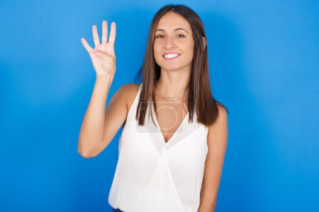 Foto de Hermosa mujer joven mostrando y señalando hacia arriba con los dedos número cuatro mientras sonríe confiado y feliz. - Imagen libre de derechos