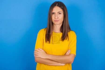 Photo for Gloomy dissatisfied beautiful young woman looks with miserable expression at camera from under forehead, makes unhappy grimace - Royalty Free Image
