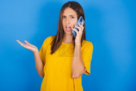 Photo for Beautiful young woman talking on the phone stressed with hand on face, shocked with shame and surprise face, angry and frustrated. Fear and upset for mistake. - Royalty Free Image