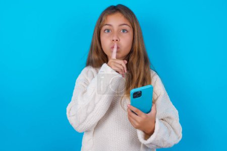 Foto de Bastante adolescente chica sosteniendo moderno gadget pedir no contar secretos - Imagen libre de derechos