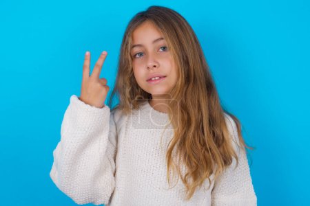 Foto de Bonita chica adolescente sonriendo y buscando amigable, mostrando el número dos o segundo con la mano hacia adelante, cuenta atrás - Imagen libre de derechos