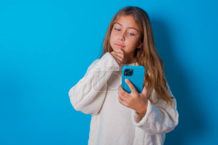 Téléchargez les photos : Réfléchi heureux jolie adolescent fille tenir regarder téléphone, copyspace - en image libre de droit