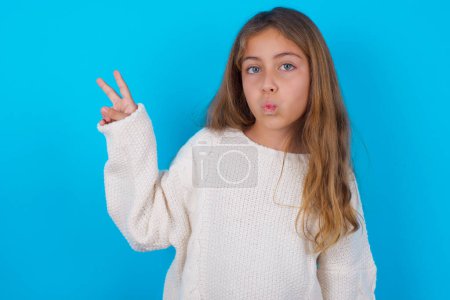 bonita chica adolescente hace gesto de paz mantiene los labios doblados muestra v signo. Concepto de lenguaje corporal