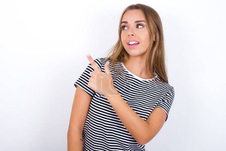 Photo for Beautiful blonde girl wearing striped t-shirt on white background glad cheery demonstrating copy space look novelty - Royalty Free Image
