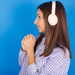 beautiful young woman wears stereo headphones listening to music concentrated and looking aside with interest.