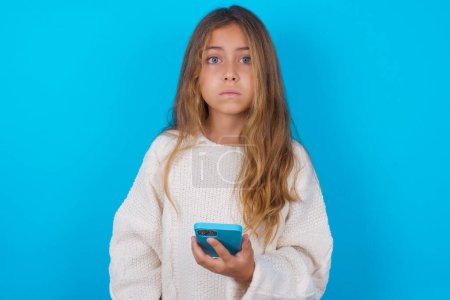 Foto de Molesto niña bastante insatisfecha adolescente utiliza aplicación de software móvil y navega información en Internet, sostiene la mano móvil moderna - Imagen libre de derechos