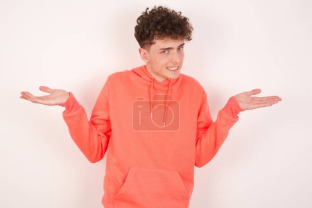 Photo for So what? Portrait of arrogant handsome young man shrugging hands sideways smiling gasping indifferent, telling something obvious. - Royalty Free Image