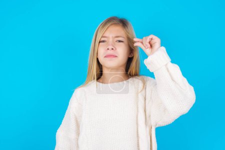 Photo for Upset pretty teen girl shapes little gesture with hand demonstrates something very tiny small size. Not very much - Royalty Free Image