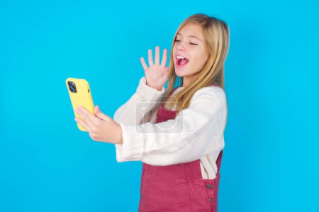 Portrait of happy friendly pretty teen girl taking selfie and waving hand, communicating on video call, online chatting.