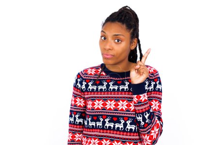 Photo for No sign gesture. Closeup portrait unhappy African American woman wearing Christmas sweater against white wall raising fore finger up saying no. Negative emotions facial expressions, feelings. - Royalty Free Image