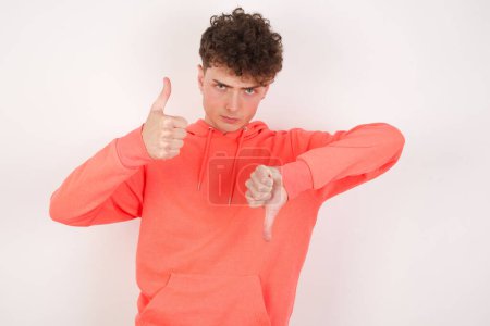 Photo for Handsome young man feeling unsure making good bad sign. Displeased and unimpressed. - Royalty Free Image
