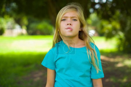Photo for Portrait of beautiful caucasian little kid girl wearing blue t-shirt standing outdoor in the park - Royalty Free Image