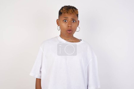 Téléchargez les photos : Femme afro-américaine portant un t-shirt blanc en vêtements décontractés exprimant dégoût, réticence, aversion, mépris d'avoir l'air tendu visage fronçant les sourcils. femme avec l'aspect agréable regardant indigné dégoûtant quelque chose - en image libre de droit