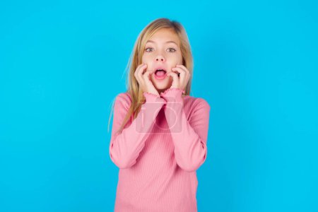 Sprachloses Teenie-Mädchen hält Hände in der Nähe geöffneten Mundes reagiert auf schockierende Nachrichten starrt verwundert in die Kamera