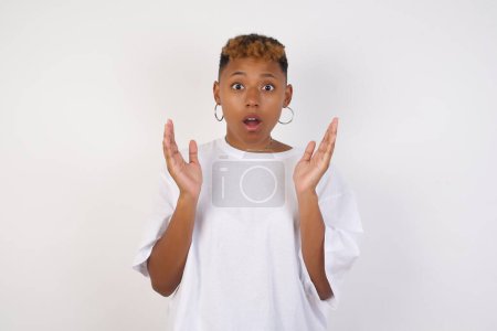 Photo for Surprise concept. Portrait of astonished beautiful african-american woman wearing white t-shirt looking surprised in full disbelief wide open mouth with hands near face with braided hair. Positive emotion facial expression body language. - Royalty Free Image