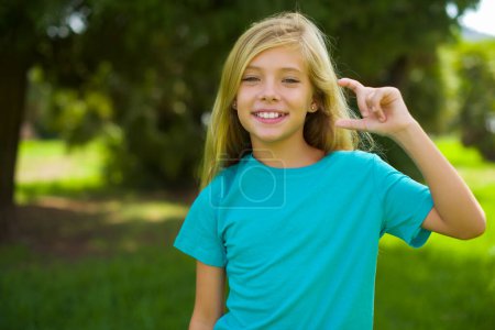 Photo for Happy cheerful pretty girl showing thumb up and pointing with the other hand. I recommend this. - Royalty Free Image