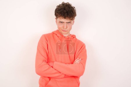 Foto de Imagen de un joven guapo enojado cruzando brazos. Mirando a la cámara con expresión decepcionada. - Imagen libre de derechos