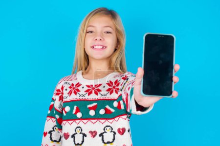 Foto de Encantadora chica bonita adorable sosteniendo un dispositivo moderno, mostrando el teléfono inteligente de pantalla negra - Imagen libre de derechos