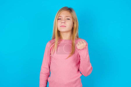 Photo for Pretty teen girl shows fist has annoyed face expression going to revenge or threaten someone makes serious look. I will show you who is boss - Royalty Free Image