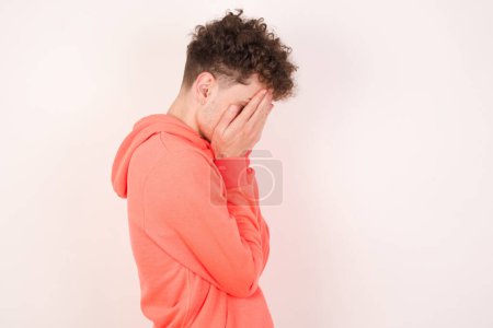 Photo for Sad handsome young man covering face with hands and crying. - Royalty Free Image