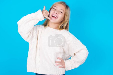 Photo for Pretty teen girl imitates telephone conversation, makes phone call gesture with hands, has confident expression. Call me! - Royalty Free Image