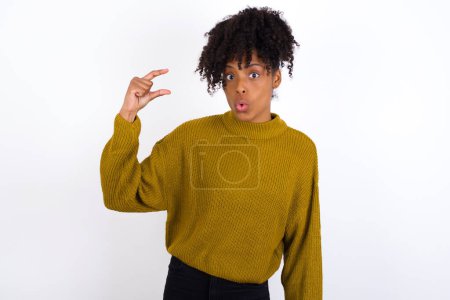 Photo for Shocked young woman shows something little with hands, demonstrates size, opens mouth from surprise. Measurement concept. - Royalty Free Image