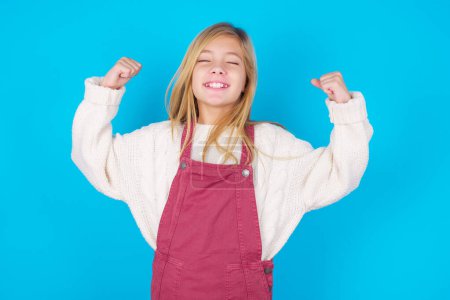 Photo for Strong powerful pretty girl toothy smile, raises arms and shows biceps. Look at my muscles! - Royalty Free Image