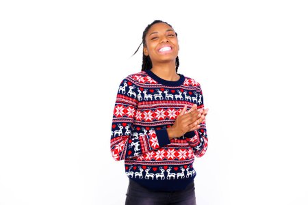 Téléchargez les photos : Femme afro-américaine portant un pull de Noël contre le mur blanc se sentant heureux, souriant et applaudissant les mains, en disant félicitations avec un applaudissement. - en image libre de droit