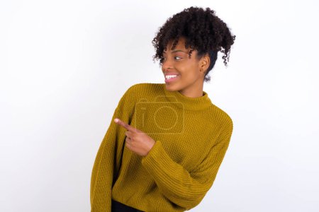 Happy cheerful smiling young woman looking and pointing aside with hand. Copy space and advertisement concept.