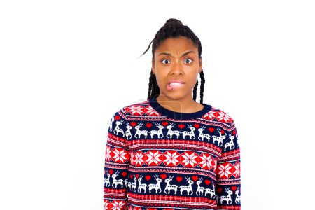 Photo for African American woman wearing Christmas sweater against white wall being nervous and scared biting lips looking camera with impatient expression, pensive. - Royalty Free Image