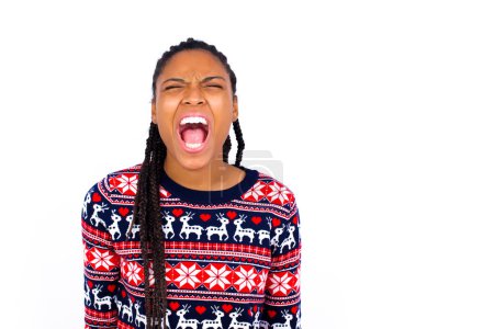 Photo for Stressful African American woman wearing Christmas sweater against white wall screams in panic, closes eyes in terror, keeps hands on head, finds out terrified news, can't believe it. - Royalty Free Image