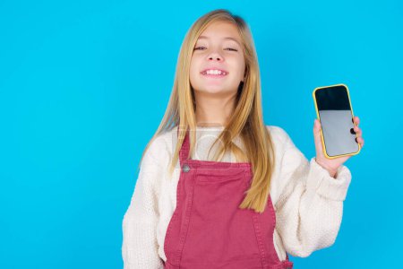 Photo for Smiling pretty teen girl showing  empty phone screen. Advertisement and communication concept. - Royalty Free Image
