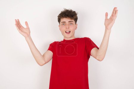 Foto de Joven guapo alegre sobre fondo blanco haciendo un gesto de bienvenida levantando los brazos sobre la cabeza. - Imagen libre de derechos