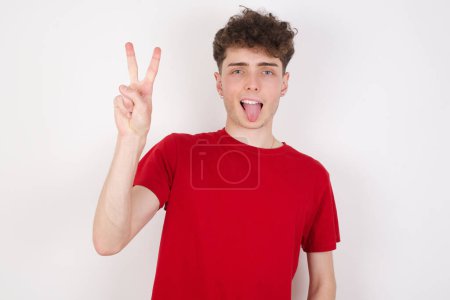 Téléchargez les photos : Beau jeune homme sur fond blanc montrant et pointant vers le haut avec les doigts numéro deux tout en souriant confiant et heureux. - en image libre de droit