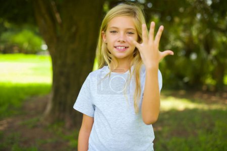 Foto de Chica bonita sonriendo y buscando amigable, mostrando el número cinco o quinto con la mano hacia adelante, cuenta atrás - Imagen libre de derechos