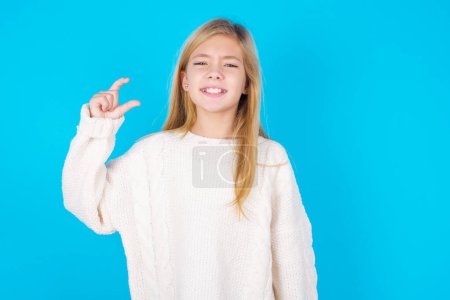 Foto de Bonita chica adolescente sonriendo y haciendo un gesto con la mano tamaño pequeño, símbolo de medida. - Imagen libre de derechos