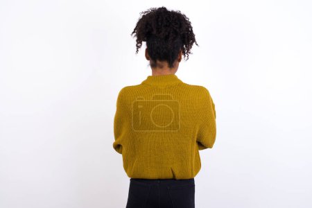 Photo for Young woman standing backwards looking away with arms on body. - Royalty Free Image