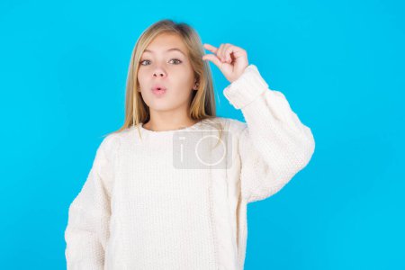 Photo for Shocked pretty teen girl shows something little with hands, demonstrates size, opens mouth from surprise. Measurement concept. - Royalty Free Image