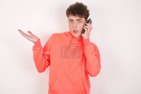 Photo for Handsome young man over white background talking on the phone stressed with hand on face, shocked with shame and surprise face, angry and frustrated. Fear and upset for mistake. - Royalty Free Image