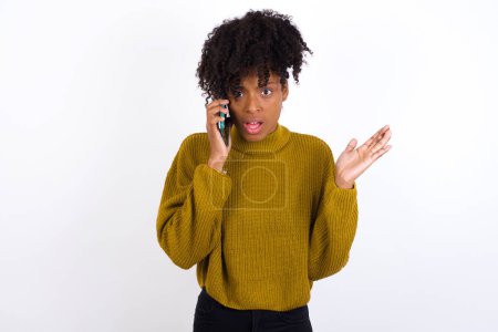 Foto de Mujer joven hablando por teléfono estresada con la mano en la cara, conmocionada con la vergüenza y la cara sorpresa, enojada y frustrada. Miedo y malestar por error. - Imagen libre de derechos