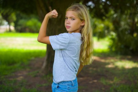 Téléchargez les photos : Forte adolescent jolie fille montrant les muscles dans le parc - en image libre de droit