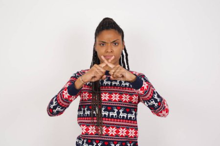 Photo for African American woman wearing Christmas sweater against white wall has rejection angry expression crossing fingers doing negative sign. - Royalty Free Image