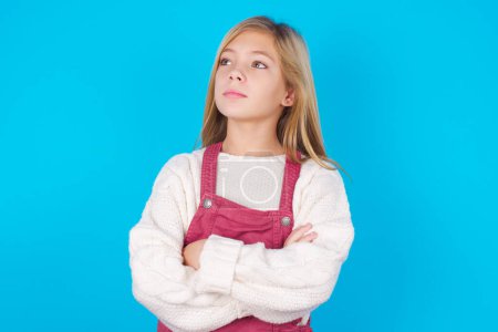 Photo for Charming thoughtful pretty girl stands with arms folded concentrated somewhere with pensive expression thinks what to do - Royalty Free Image