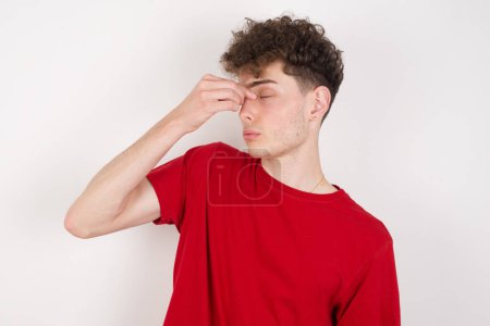 Photo for Very upset, handsome young man over white background touching nose between closed eyes, wants to cry, having stressful relationship or having troubles with work - Royalty Free Image