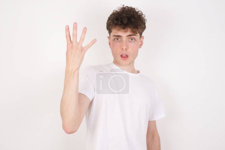 Foto de Joven guapo sobre fondo blanco sonriendo y mirando amigable, mostrando el número cuatro o cuarto con la mano hacia adelante, cuenta atrás - Imagen libre de derechos