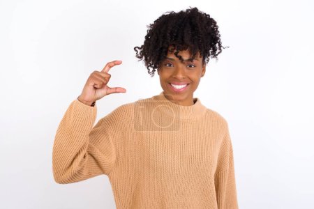 Téléchargez les photos : Jeune femme souriante et gestuelle avec la main petite taille, symbole de mesure. - en image libre de droit