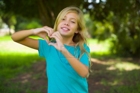 Hübsches Mädchen zeigt Herz-Geste im Park