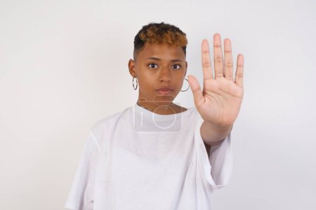 Photo for Young beautiful black woman doing stop gesture with palm of the hand. Warning expression with negative and serious gesture on the face isolated over gray background. - Royalty Free Image